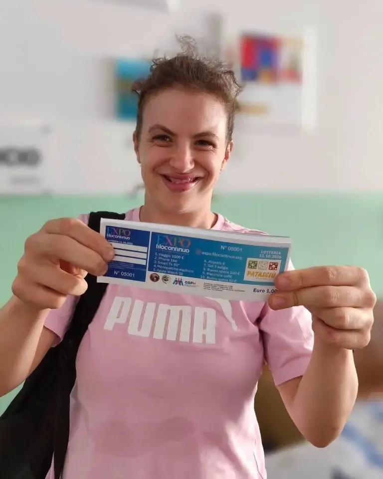 Melissa, utente di Filo Continuo, sorride tenendo in mano un biglietto della Lotteria EXPO Filo Continuo.